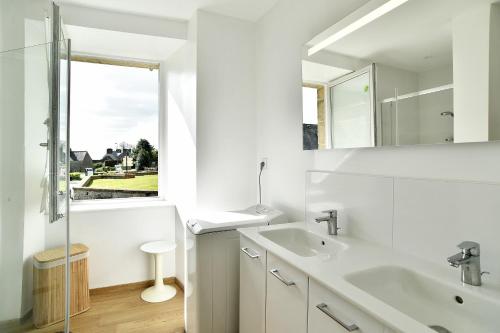 a white bathroom with a sink and a mirror at La tourelle du Val-d'Arguenon in Pluduno