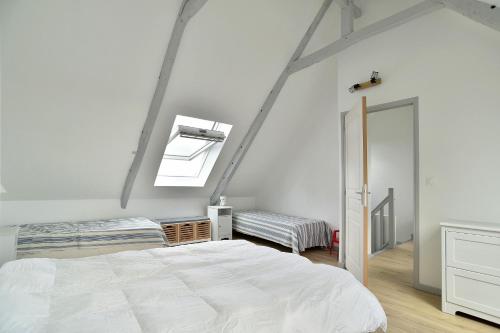 a white bedroom with a bed and a window at La tourelle du Val-d'Arguenon in Pluduno