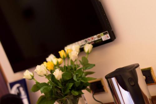 a vase of flowers sitting on a desk with a tv at Hotel Polo in Rimini
