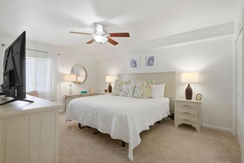 a white bedroom with a bed and a flat screen tv at SeaSpray Riverside 312 in Perdido Key