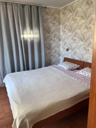a bedroom with a bed with white sheets and a curtain at Apartment Dream in Boreti