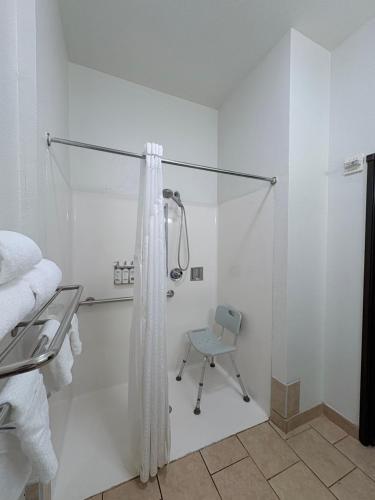 a white bathroom with a shower and a chair at Country Inn & Suites by Radisson, Terrell in Terrell