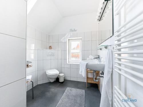 a white bathroom with a toilet and a sink at Hus Krüüzpadd boben in Cuxhaven