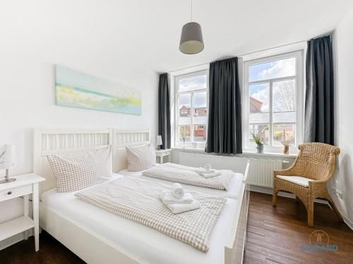 a bedroom with two beds and a desk and windows at Hus Krüüzpadd unnen in Cuxhaven