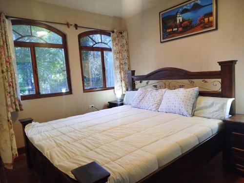 a bedroom with a large bed with two windows at Hospedaje in San Pablo La Laguna