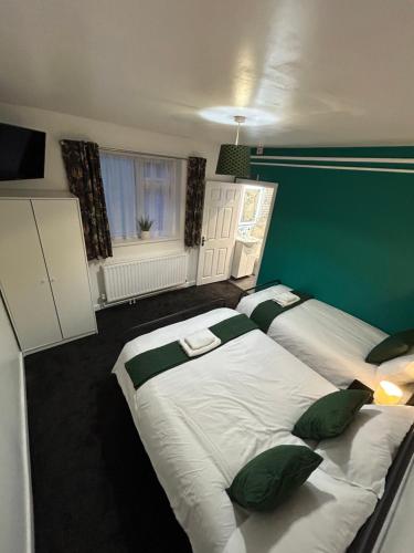a bedroom with two beds and a green wall at Spaghetti House - 6 Bedroom Contractor House Sleeps 12 Parking for 3 Vans Bromford Duddeston Fort Dunlop Star City Saltley Viaduct HS2 in Birmingham