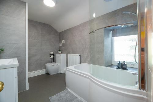 a white bathroom with a tub and a toilet at 3BDR Town House in the Heart of Holyhead - Free Onsite Parking in Holyhead
