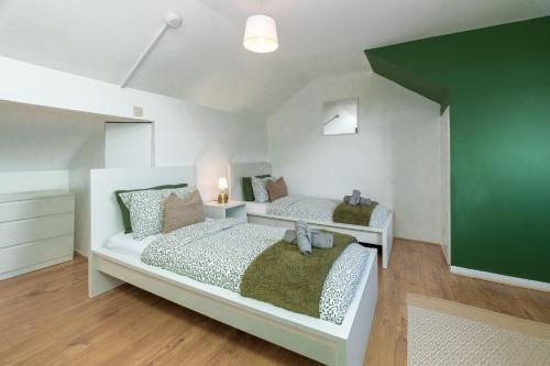a bedroom with two beds and a green wall at 3BDR Town House in the Heart of Holyhead - Free Onsite Parking in Holyhead