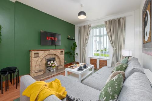 a living room with a gray couch and a fireplace at 3BDR Town House in the Heart of Holyhead - Free Onsite Parking in Holyhead