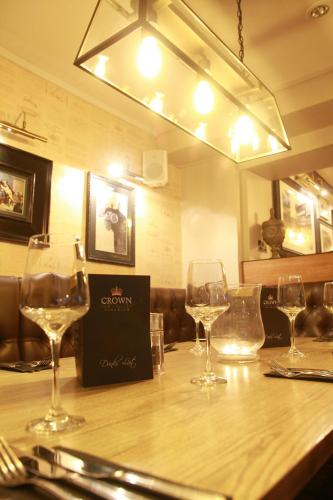 four wine glasses sitting on a table in a restaurant at Crown Hotel in Nantwich