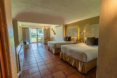 une chambre d'hôtel avec deux lits et une table dans l'établissement Real de Chapala, à Ajijic