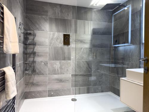 a bathroom with a glass shower with a sink at Beautiful River View with Sauna in Llandysul