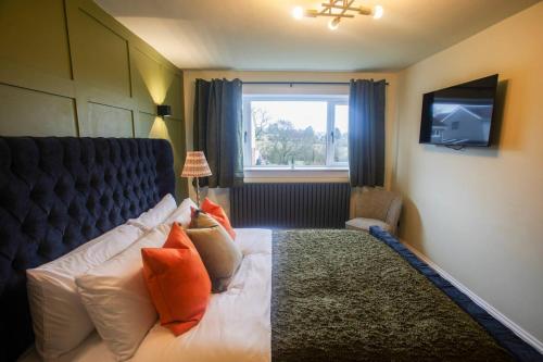 a bedroom with a bed with orange pillows and a window at Unique 3 Bed Home, Stewarton in Stewarton