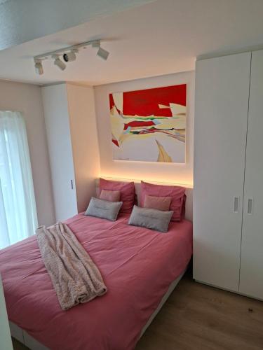 a bedroom with a large bed with pink sheets at Meerzicht-Laguna in Knokke-Heist