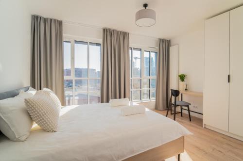 a white bedroom with a large bed and windows at Prime Apartments Gdańsk in Gdańsk
