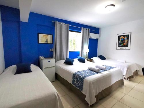 ein Schlafzimmer mit zwei Betten und einer blauen Wand in der Unterkunft Hotel Arthaus in Asunción