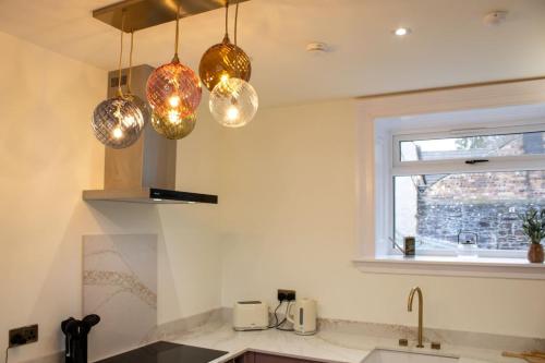 a kitchen with three lights hanging over a sink at Unique 1 Bed Apartment, Auchterarder in Auchterarder
