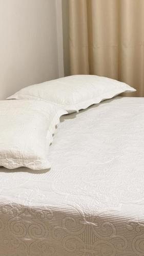 a white bed with two pillows on top of it at Apto Centro de Sinop - 720C in Sinop