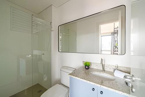 a bathroom with a toilet and a sink and a mirror at Flipchave | Highline design in Joinville