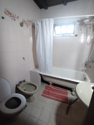 a bathroom with a toilet and a tub and a sink at Casa Garú in Paso de los Libres