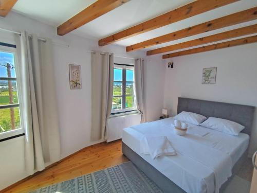 a bedroom with a white bed and two windows at Villa Ioanna in Agkidia