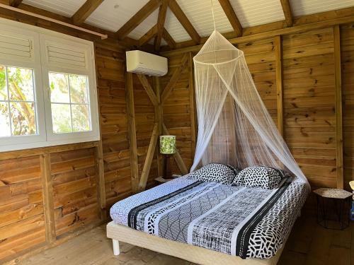 a bedroom with a bed in a log cabin at Ti Bwa in Sainte-Luce