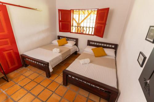 two beds in a small room with a window at El cantor Finca hotel in Quimbaya