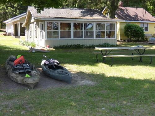 three kayaks sitting in the grass in front of a house at Sandy Bottom Cottage on Intermediate Lake in Bellaire