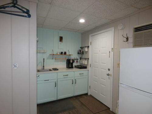 a kitchen with white cabinets and a white door at Happy Hour at Windcliff! Studio condo at Shanty Creek Resort in Bellaire