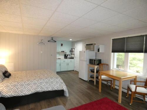 a bedroom with a bed and a table and a kitchen at Happy Hour at Windcliff! Studio condo at Shanty Creek Resort in Bellaire