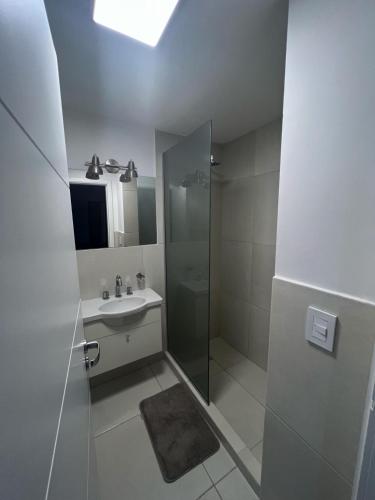 a white bathroom with a sink and a shower at KIRA HAUS, North Green in Villa Allende