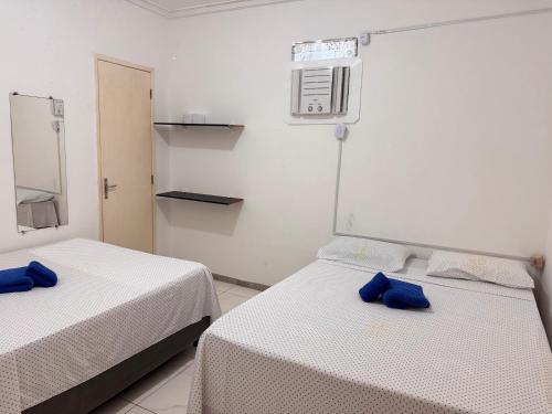 two beds in a room with blue pillows at SR Hotel e Pousada Pirambu in Pirambu