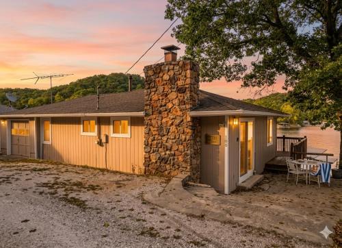 a small house with a stone chimney and a table at Markley Manor - Beautiful views in Sunrise Beach