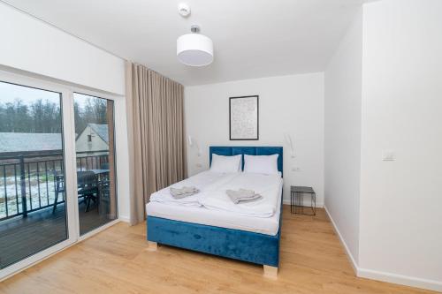 a bedroom with a blue bed and a balcony at Apartamenty Mazurska Strefa in Pisz