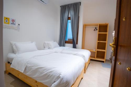 two twin beds in a room with a window at Bait mutirah guesthouse in Muscat
