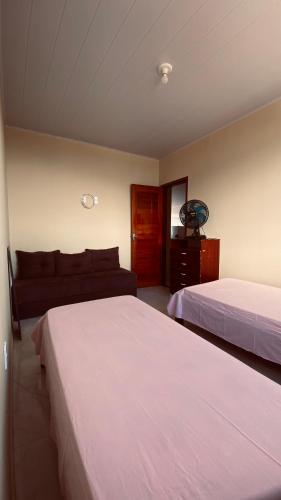 a bedroom with two beds and a couch at Quarto Triplo in Areia