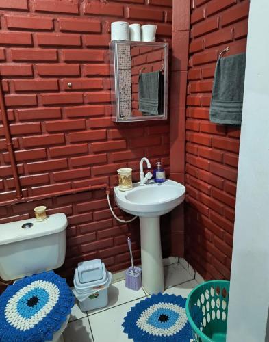a bathroom with a sink and a red brick wall at Espaço Pires in Jaciara