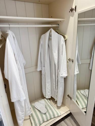 a closet with white robes and a mirror at Altons Bothy Guest House in Kinmuck