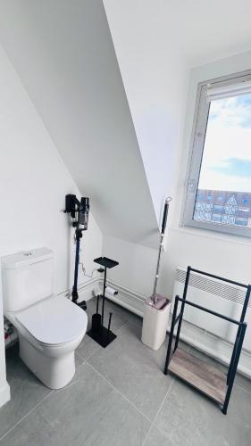 a white bathroom with a toilet and a window at Cabourg-Angle bleu in Cabourg
