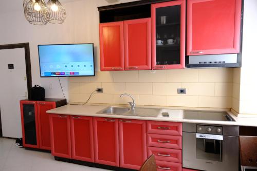 a kitchen with red cabinets and a sink and a tv at Sea View Family Apartment Durres in Durrës