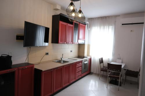 a kitchen with red cabinets and a sink and a window at Sea View Family Apartment Durres in Durrës