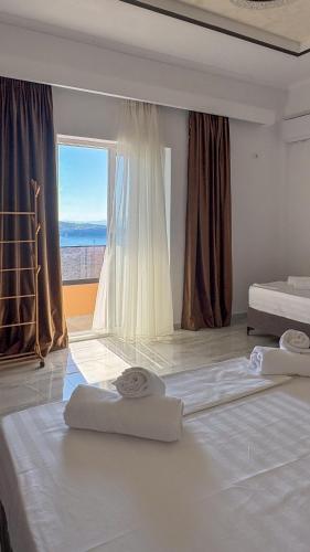 a bedroom with two beds and a large window at Thea Rooms in Himare