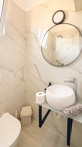 a white bathroom with a sink and a mirror at Thea Rooms in Himare