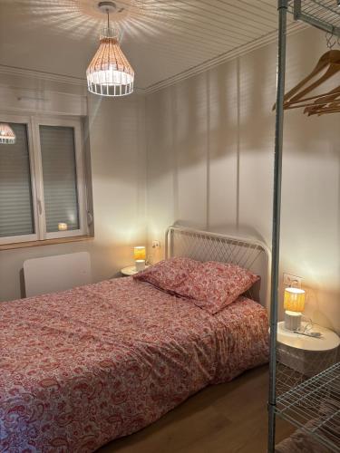 a bedroom with a bed and two tables and a chandelier at Maison rénovée - 2 chambres - 4 pers - L'Abeel Escapade in Bailleul