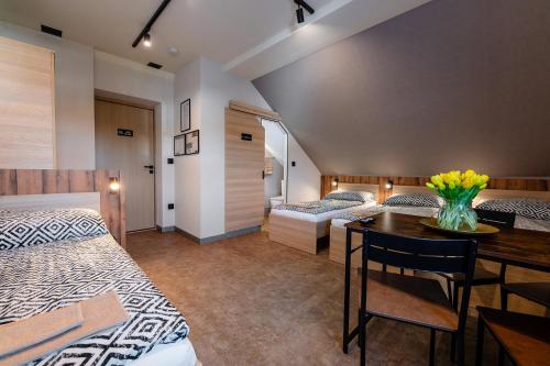 a bedroom with two beds and a table with flowers on it at KARCZMA-KOSZWICE in Koszwice