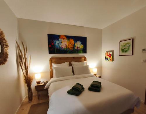 a bedroom with a white bed with two green towels on it at VILLA ADOYA Chambre d'hôtes Aigues-Mortes intra muros au calme climatisation réversible PISCINE WIFI ascenseur PARKING gratuit in Aigues-Mortes