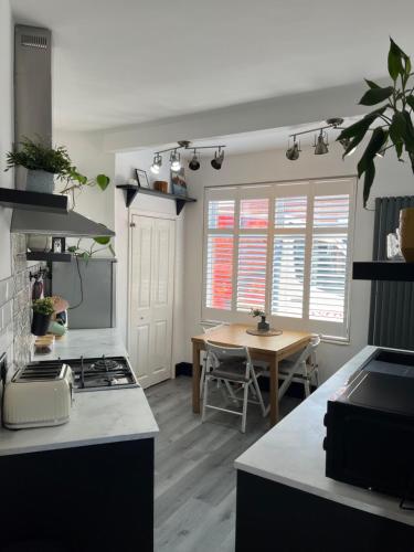 a kitchen with a stove and a table in it at Hoole House- Recently decorated, bright and modern 2 bedroom house, close to Chester train station and the City Centre in Chester