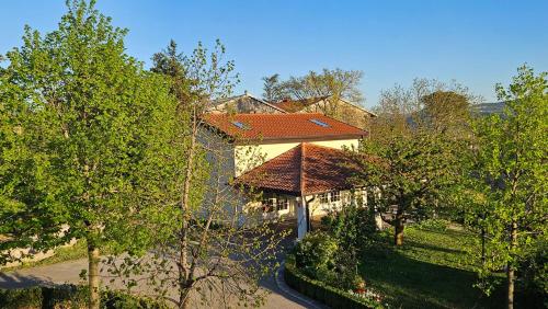 a house with a red roof and some trees at Apartments Kompara in Ajdovščina