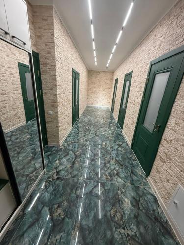 a corridor with green doors and a stone floor at Shayxul Islam 5 in Bukhara