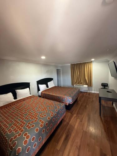 a hotel room with two beds and a desk at Colony Inn in Buena Park